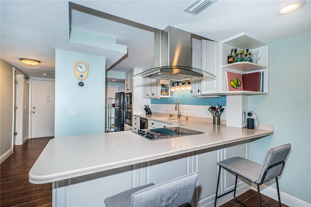 kitchen featuring kitchen peninsula, black electric stovetop, dark wood-type flooring, and wall chimney range hood