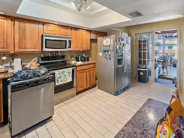 kitchen featuring dark stone counters, a tray ceiling, and stainless steel appliances