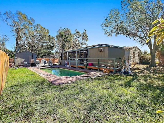 back of house with a storage unit, a fenced in pool, and a yard