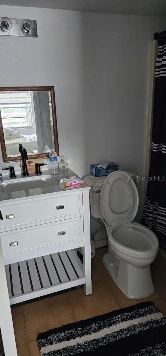 bathroom with a shower with curtain, vanity, toilet, and tile patterned flooring