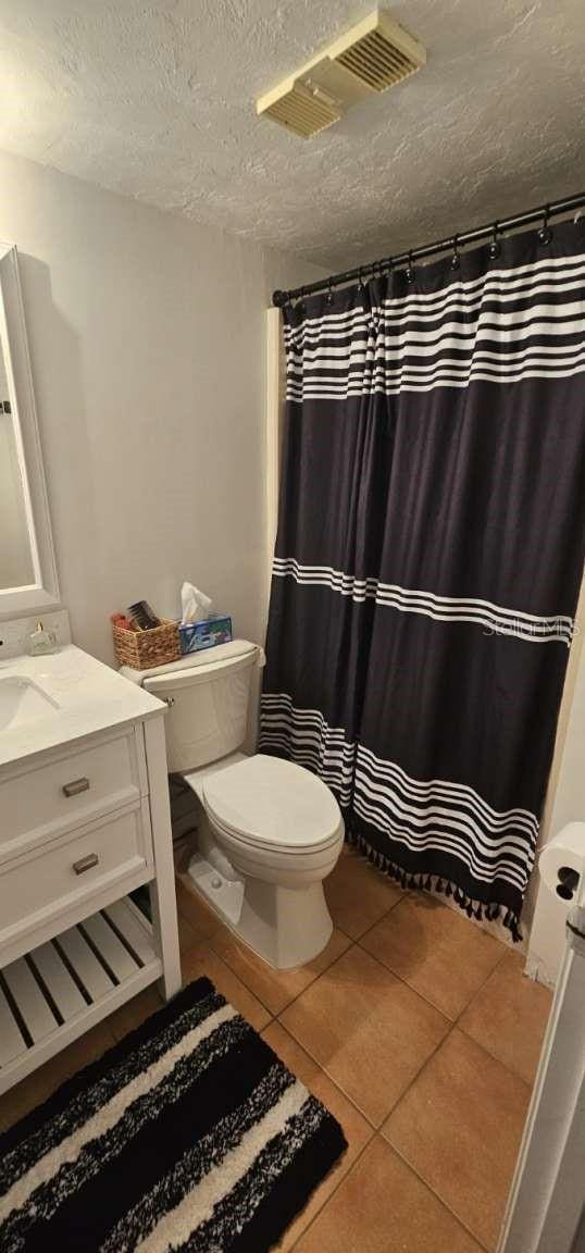 bathroom with vanity, toilet, tile patterned flooring, and a textured ceiling