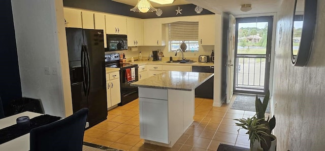 kitchen featuring sink, white cabinetry, light tile patterned floors, a kitchen island, and black appliances