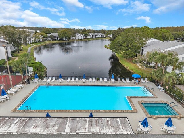 community pool featuring a patio, a water view, and fence