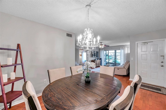 dining room with visible vents, an inviting chandelier, a textured ceiling, wood finished floors, and baseboards