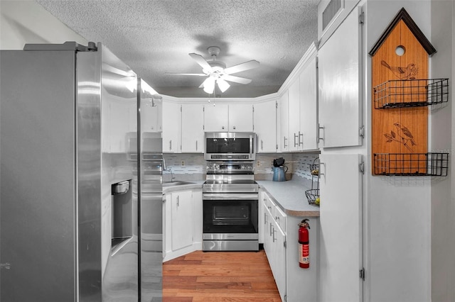 kitchen with a ceiling fan, visible vents, light wood-style floors, light countertops, and appliances with stainless steel finishes