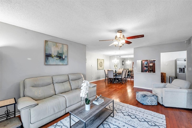 living room featuring a textured ceiling, baseboards, wood finished floors, and ceiling fan with notable chandelier