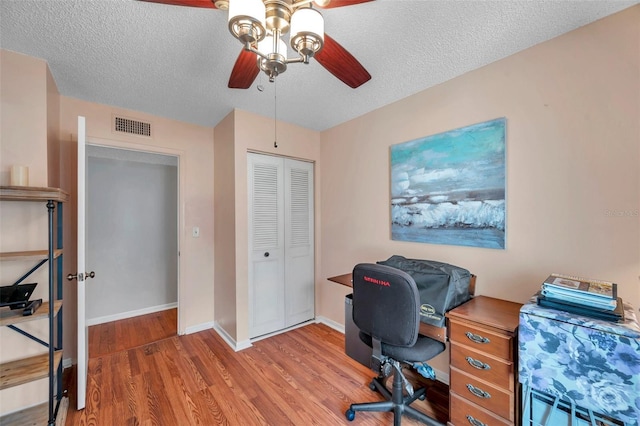 home office with baseboards, a textured ceiling, visible vents, and wood finished floors