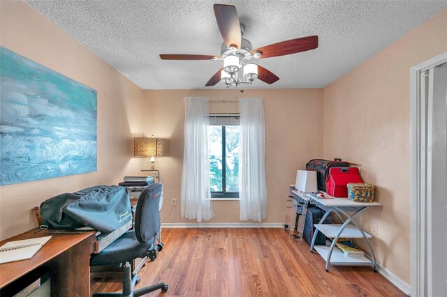 home office with a textured ceiling, ceiling fan, wood finished floors, and baseboards