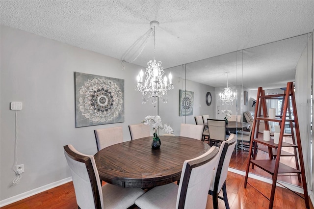 dining area with a chandelier, a textured ceiling, and wood finished floors