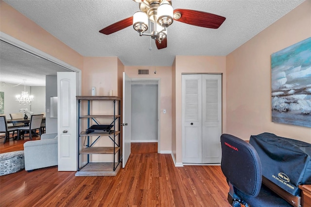 office area with a textured ceiling, wood finished floors, a ceiling fan, visible vents, and baseboards