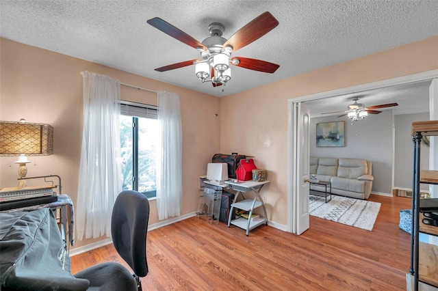 home office with a textured ceiling, baseboards, and wood finished floors