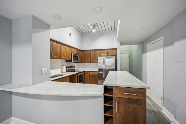 kitchen with tasteful backsplash, kitchen peninsula, dark hardwood / wood-style floors, and appliances with stainless steel finishes