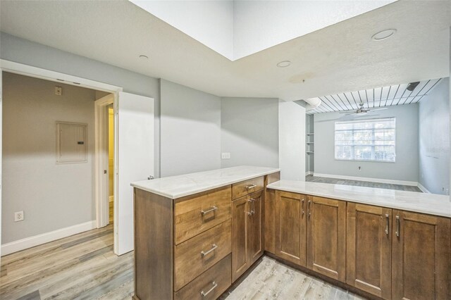 kitchen featuring vaulted ceiling, ceiling fan, a textured ceiling, light hardwood / wood-style floors, and kitchen peninsula