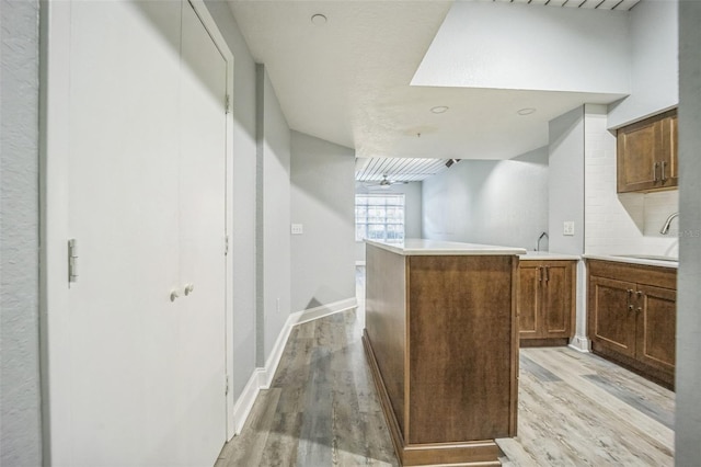 kitchen with kitchen peninsula, light hardwood / wood-style floors, and sink