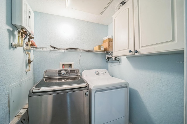 washroom with cabinets, water heater, and washer and dryer