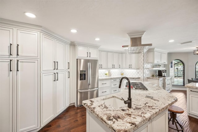 kitchen with range hood, dark wood finished floors, stainless steel appliances, white cabinets, and a sink