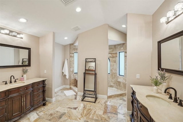 full bath with two vanities, a sink, baseboards, and walk in shower