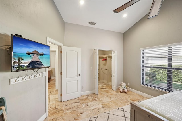 bedroom with high vaulted ceiling, a walk in closet, visible vents, and baseboards