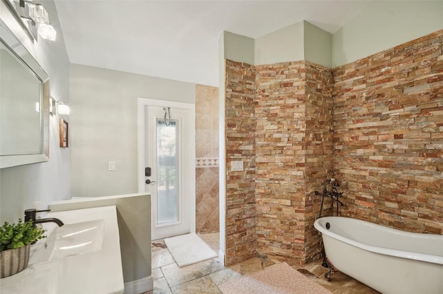 bathroom featuring a soaking tub, walk in shower, vanity, and stone tile floors