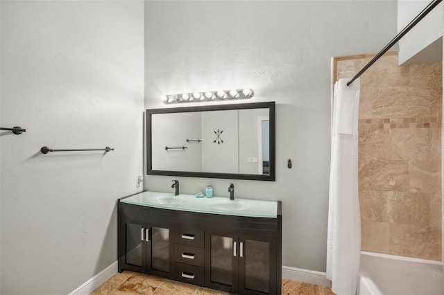 full bath with double vanity, baseboards, and a sink