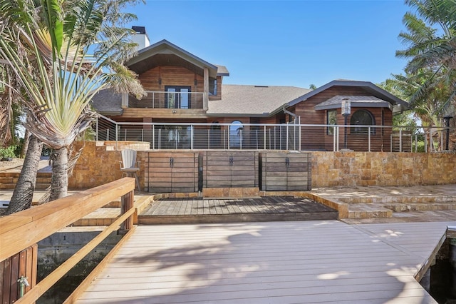 back of property with a balcony and a shingled roof