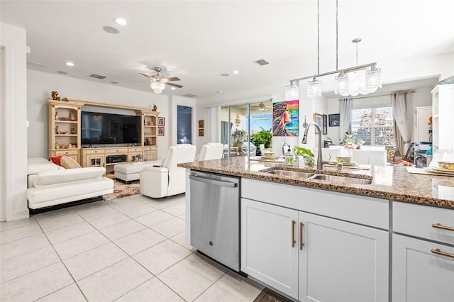 kitchen with sink, hanging light fixtures, light stone counters, stainless steel dishwasher, and ceiling fan with notable chandelier