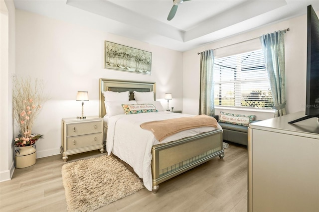 bedroom with a tray ceiling, ceiling fan, and light hardwood / wood-style floors