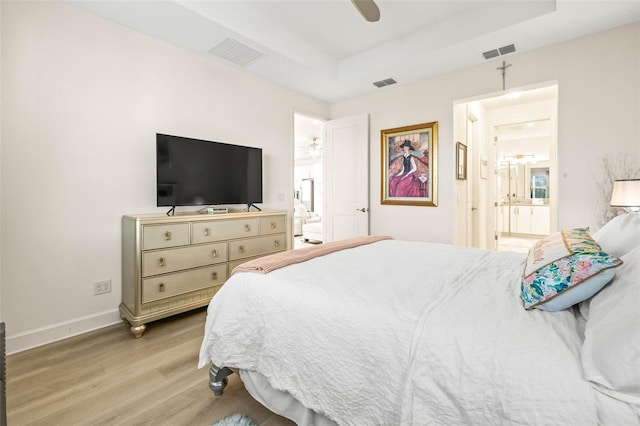 bedroom with ceiling fan, light wood-type flooring, and ensuite bath