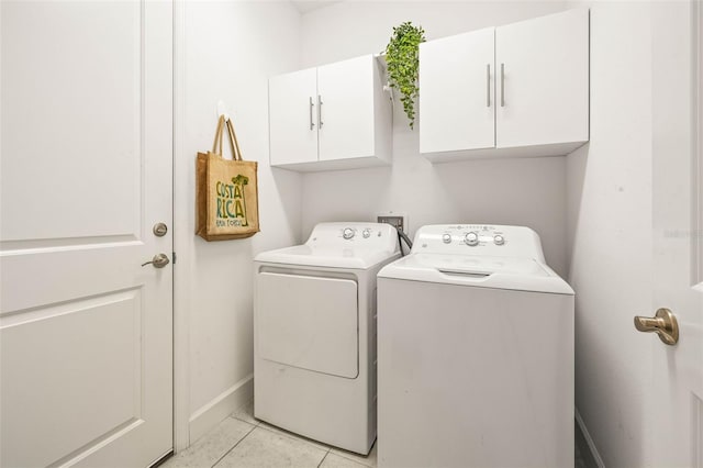 laundry room with washer and dryer, cabinets, and light tile patterned floors