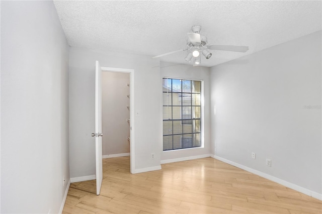 spare room with ceiling fan, light wood-type flooring, and a textured ceiling