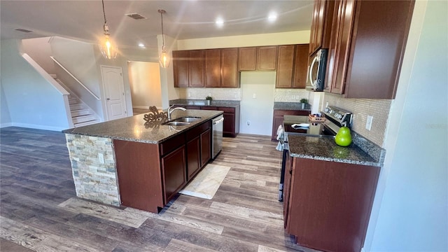 kitchen featuring wood-type flooring, sink, stainless steel appliances, and an island with sink