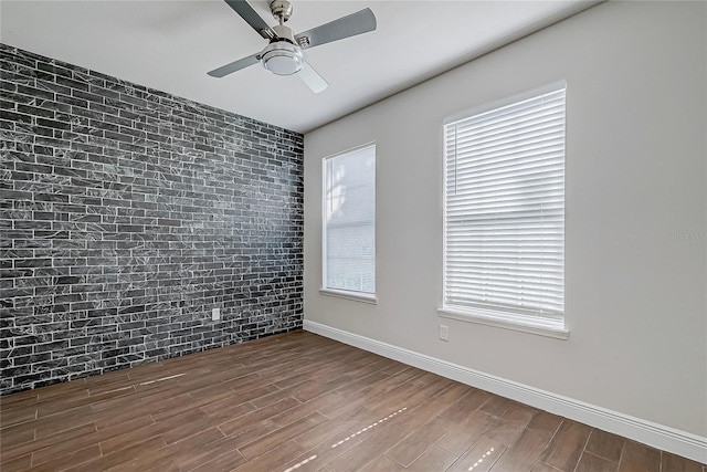 spare room with hardwood / wood-style floors, ceiling fan, and brick wall