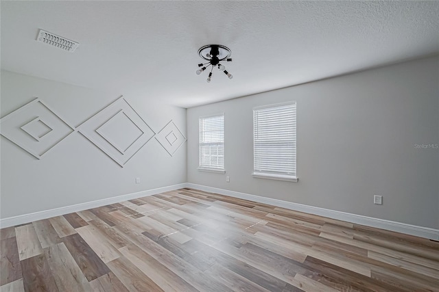 spare room with light hardwood / wood-style flooring and a textured ceiling