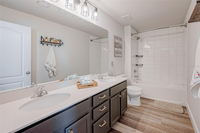 full bathroom with hardwood / wood-style floors, vanity, toilet, and tiled shower / bath