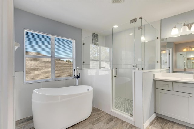 bathroom featuring hardwood / wood-style floors, vanity, and shower with separate bathtub