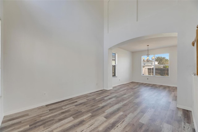 unfurnished living room with an inviting chandelier and light wood-type flooring