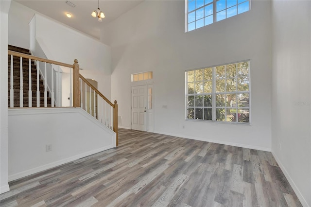 entryway with a towering ceiling, a notable chandelier, and hardwood / wood-style flooring