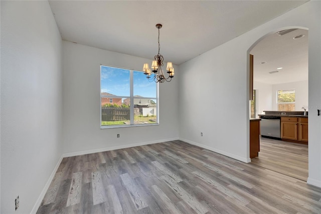 unfurnished dining area featuring a chandelier, light wood-type flooring, and sink