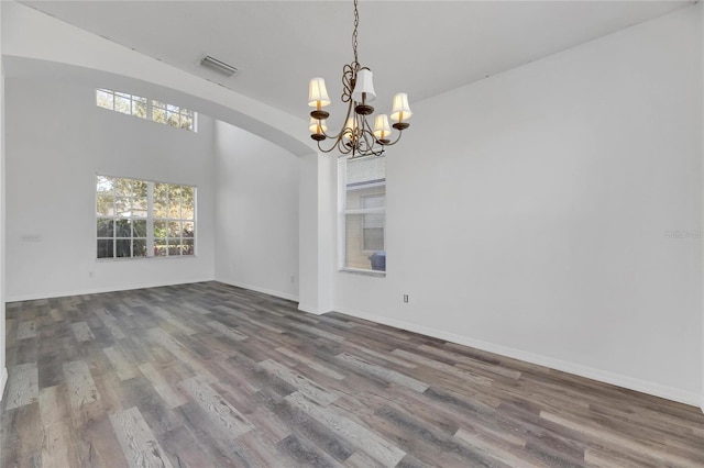 empty room with hardwood / wood-style floors and a chandelier