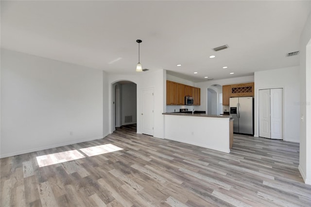 kitchen with stainless steel appliances, hanging light fixtures, and light hardwood / wood-style floors