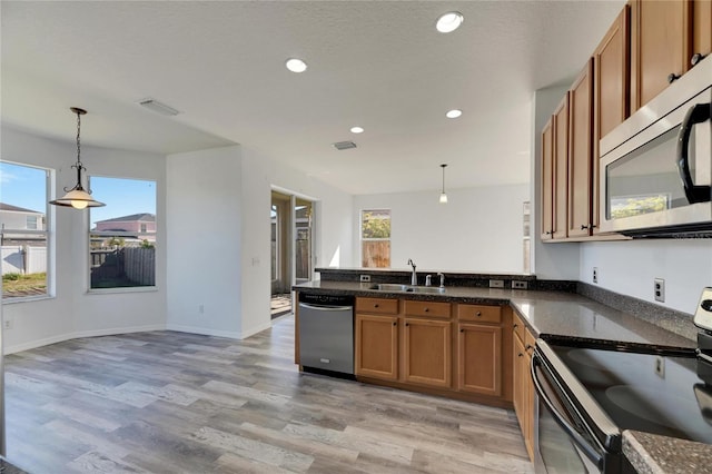 kitchen with a wealth of natural light, hanging light fixtures, and stainless steel appliances