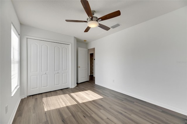 unfurnished bedroom featuring multiple windows, a closet, and hardwood / wood-style floors