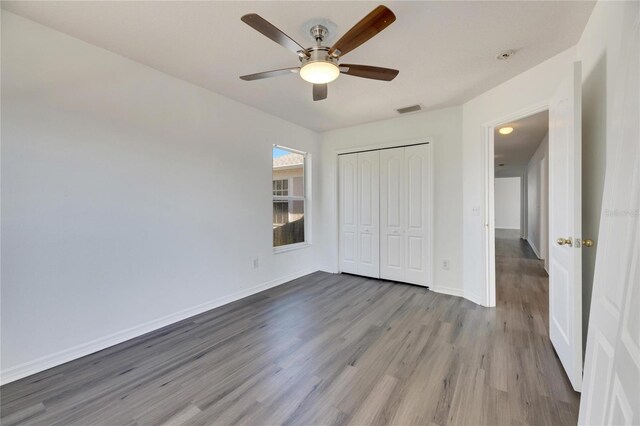 unfurnished bedroom featuring ceiling fan, a closet, and light hardwood / wood-style flooring