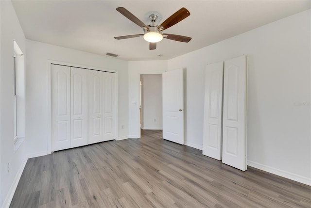 unfurnished bedroom featuring ceiling fan, a closet, and light wood-type flooring