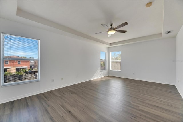 spare room featuring dark hardwood / wood-style floors, ceiling fan, and a raised ceiling