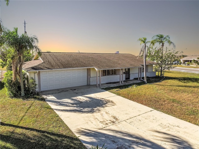 single story home with a lawn, covered porch, and a garage