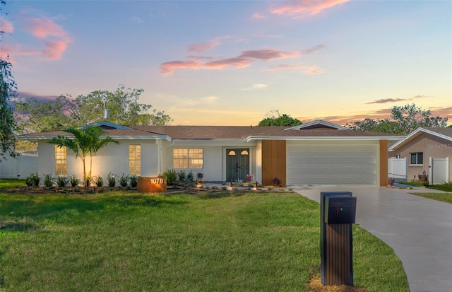 ranch-style home featuring a garage and a lawn