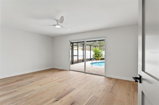 spare room featuring light wood finished floors, a ceiling fan, a sunroom, and baseboards