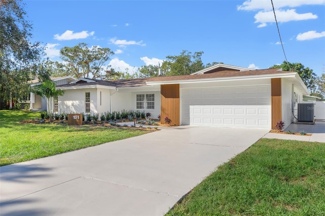 ranch-style house featuring driveway, an attached garage, central air condition unit, a front yard, and stucco siding