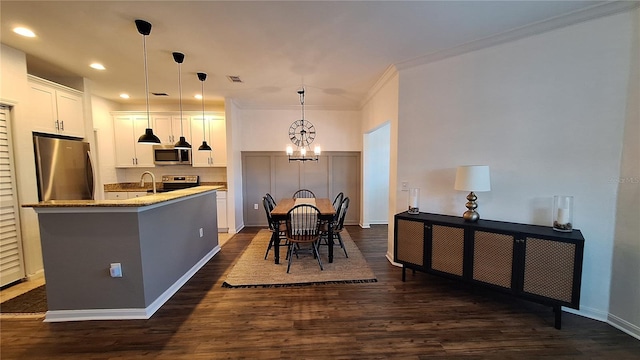 kitchen featuring a kitchen island with sink, an inviting chandelier, white cabinets, hanging light fixtures, and appliances with stainless steel finishes